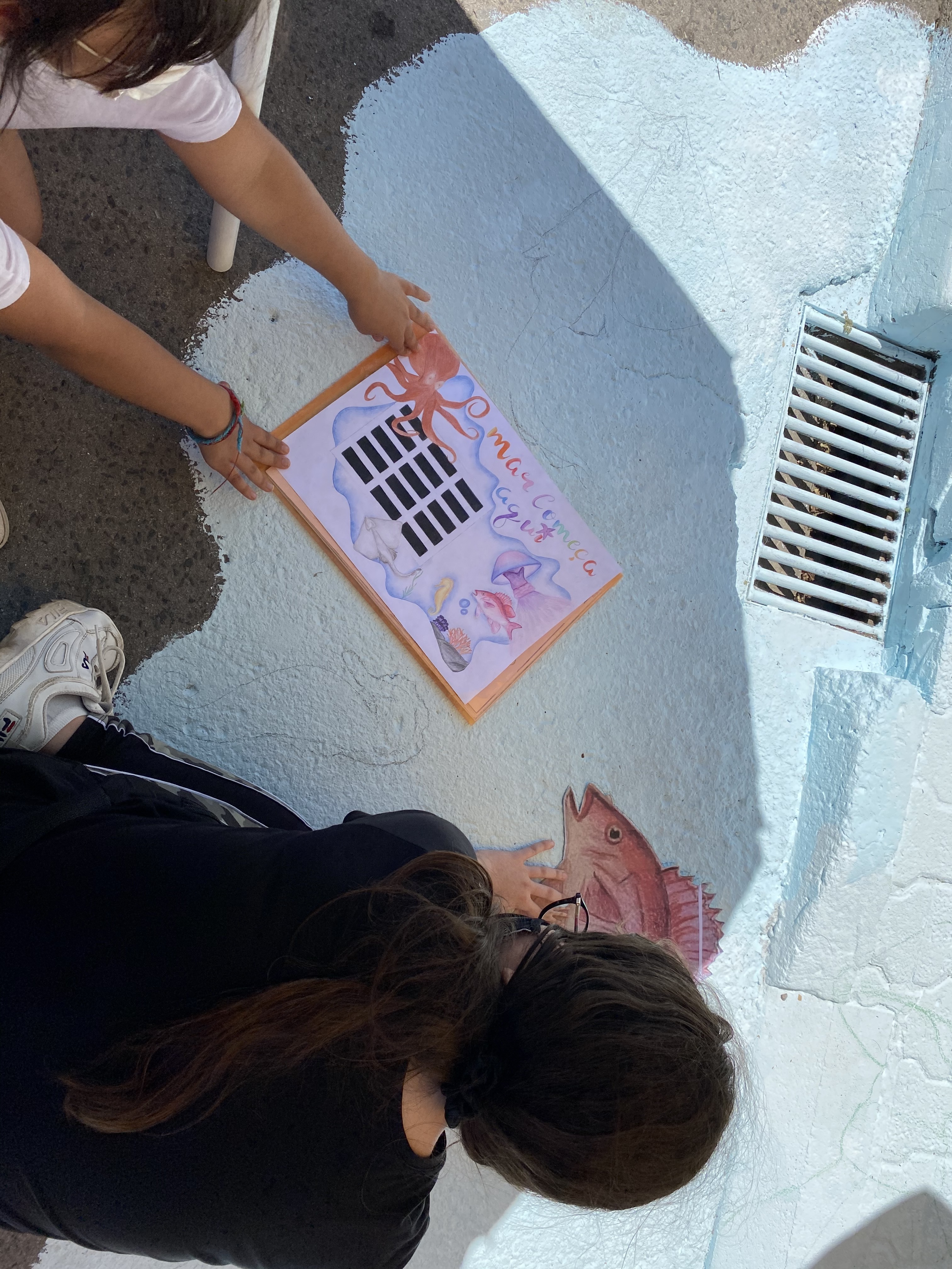 Os  alunos começaram por marcar a azul e branco a zona do mar, depois começaram a marcar os desenhos com os moldes que fizeram.