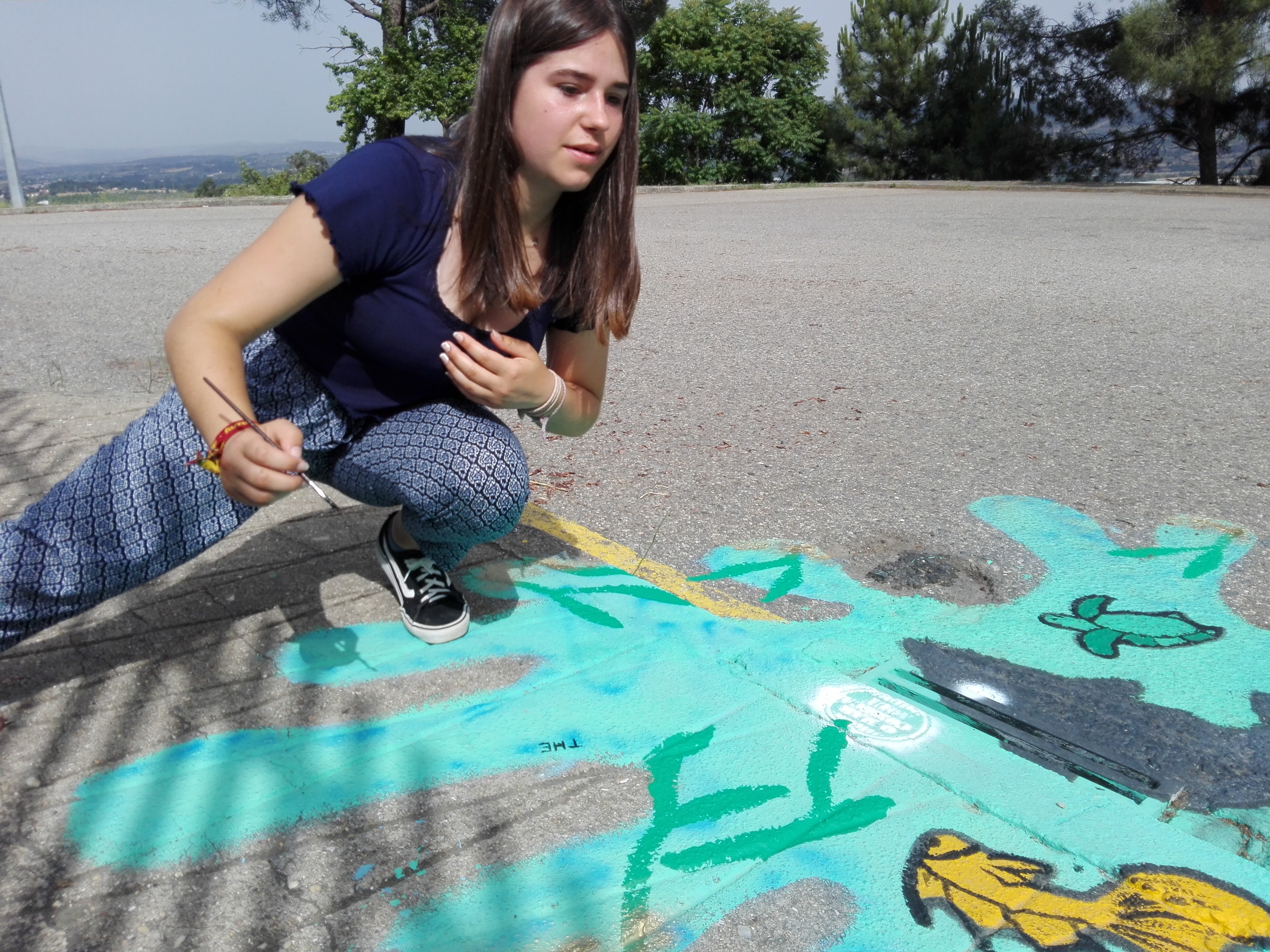 A Francisca a dar os últimos retoque na pintura exterior da escola EBT, junto ao estacionamento
