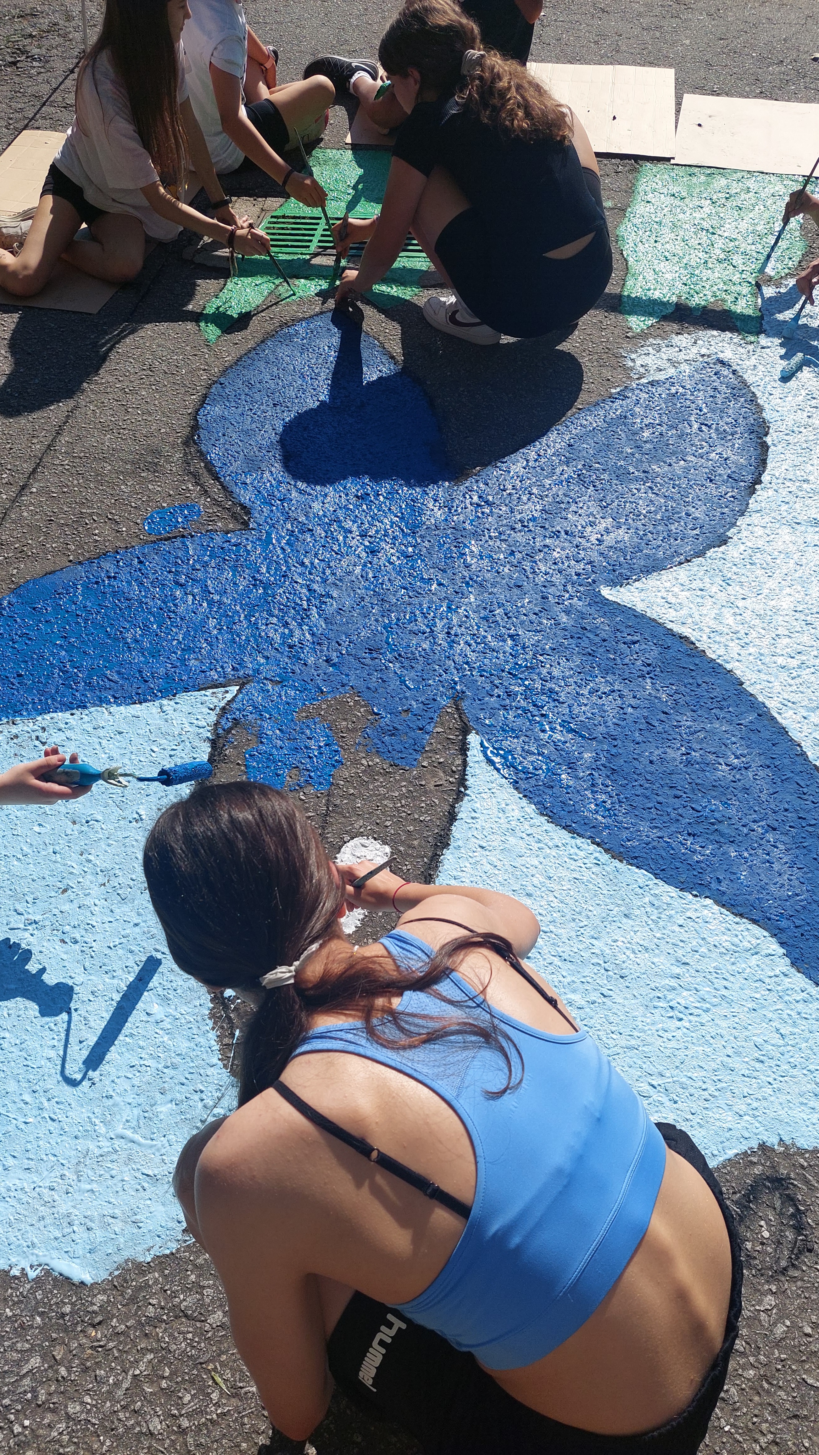Vários alunos a pintarem a sarjeta no exterior da Escola Dr. Francisco Sanches, em Braga, com várias cores, entre as quais uma aluna a pintar os olhos da estrela do mar - Travessa do Taxa